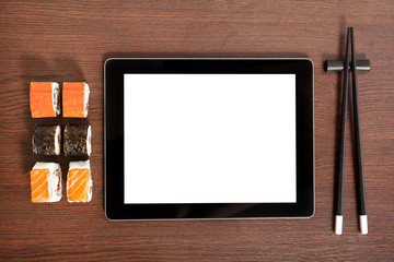 Tablet on a table near sushi