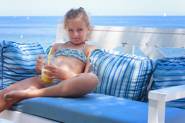 Girl drinking cold juice by the sea