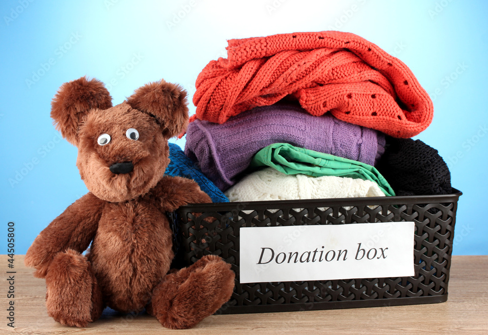 Donation box with clothing on blue background close-up