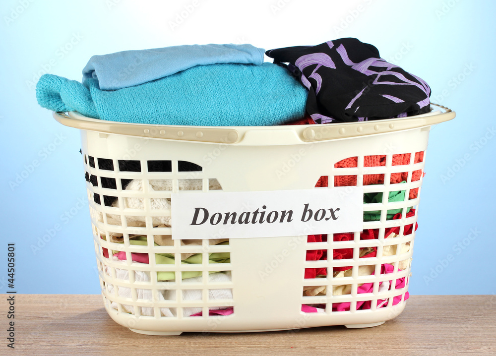 Donation box with clothing on blue background close-up