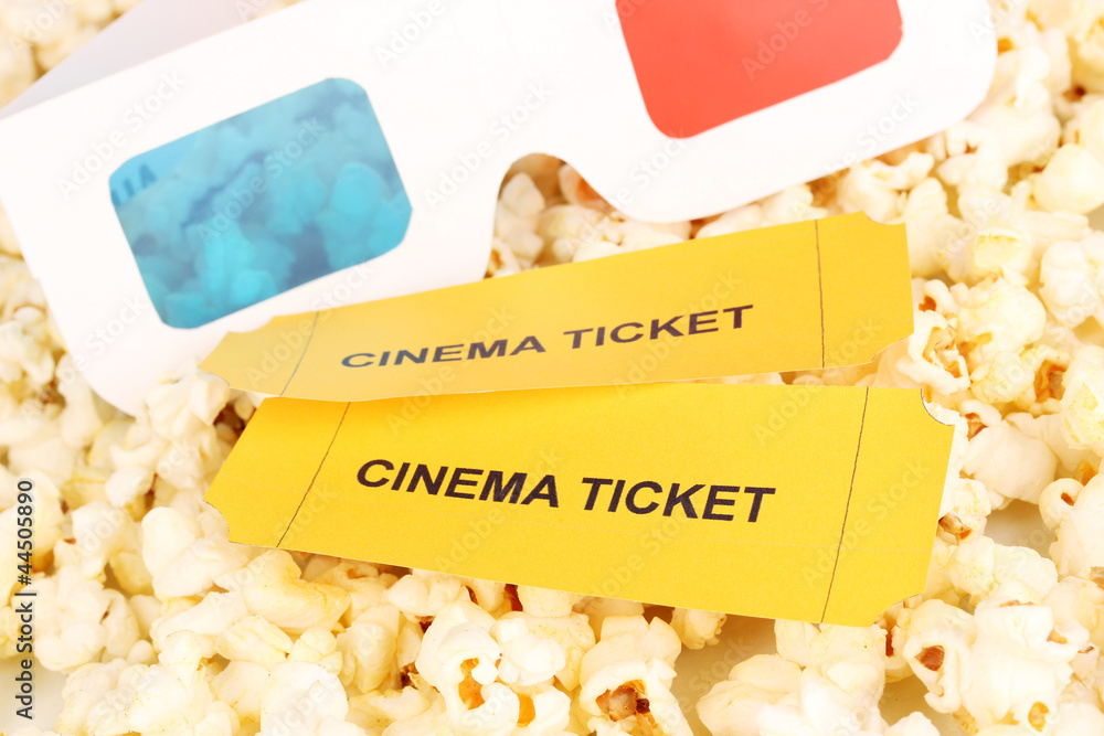 cinema tickets and glasses on popcorn background