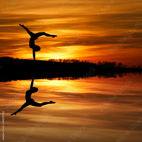 Plakat na papierze fotorealistycznym Sylwetka kobiet gimnastyk robi handstand w zachód słońca