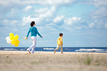 Mother and little son with ballons on the beach