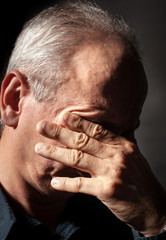 elderly man with face closed by hand