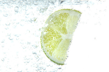 Poster - slice of lime in the water with bubbles, isolated on white