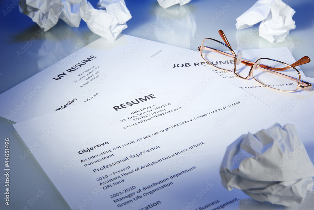 Closeup of resume with glasses on blue background