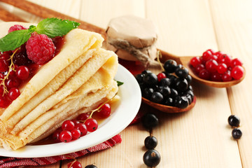 Wall Mural - Delicious pancakes with berries, jam and honey on wooden table