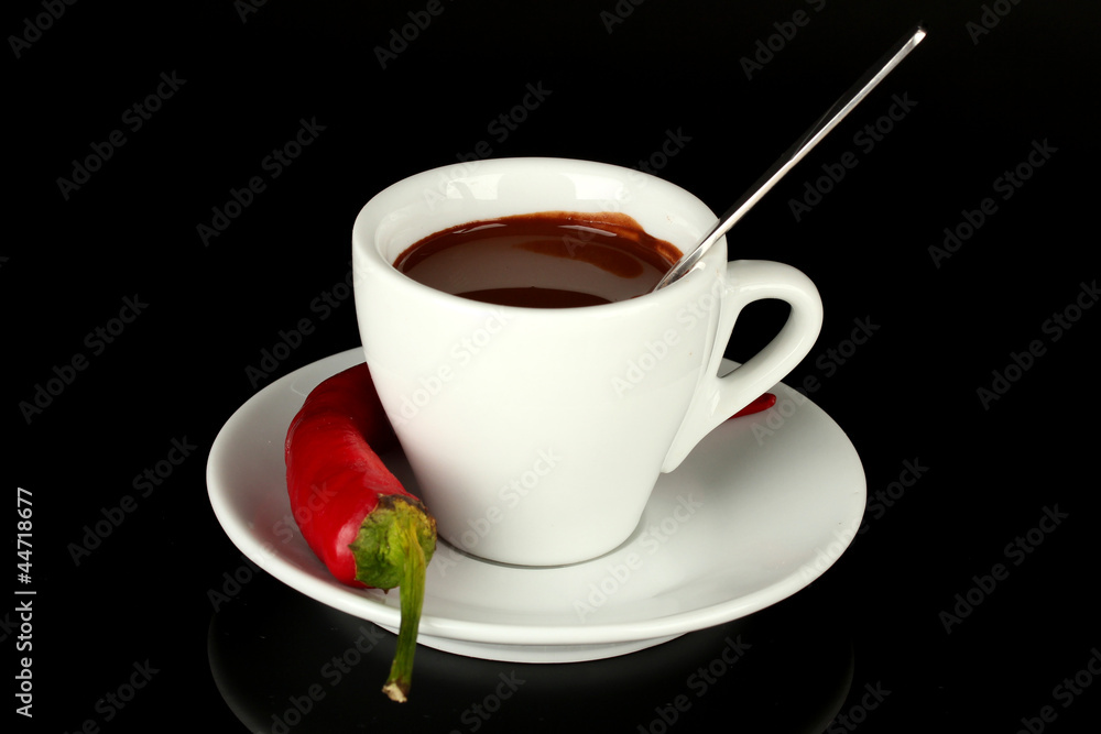 white cup with hot chocolate and chili pepper isolated on black