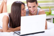 © luckybusiness - Couple enjoying using laptop in bed