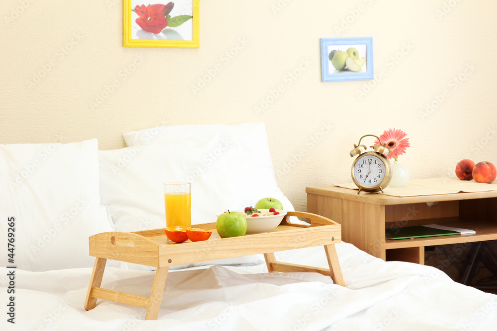 wooden tray with light breakfast on bed