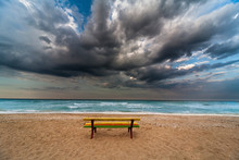 Colorful Bench On A Beach Dramatic Clouds And Sea As Backdrop