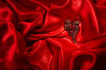Jewelry over red silk background. Gem brooch.,