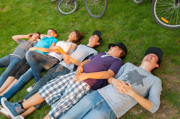 Wall Mural - Teenage boys and girls lying on the grass after riding bicycles