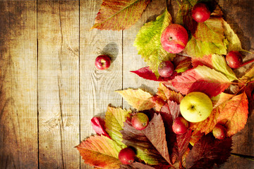 Autumn apples and leaves on wooden table with grunge texture