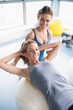 © WavebreakmediaMicro - Woman doing sit ups on exercise ball with trainer
