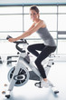 © WavebreakmediaMicro - Smiling woman training on exercise bike