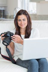 Wall Mural - Brunette holding a camera and a laptop