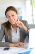 © goodluz - Smiling businesswoman sitting at her desk