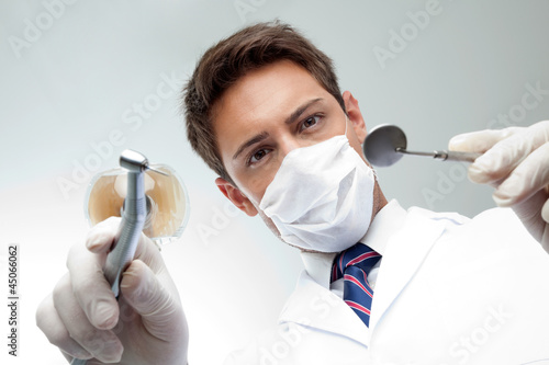 Fotoboard na płycie Dentysta trzyma kątowe lustro i wiertło
