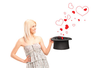 Poster - Smiling female holding a top hat and hearts around