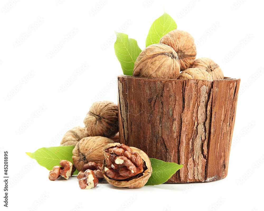 walnuts with green leaves in woooden vase, isolated on white