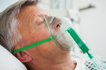 man in bed with oxygen mask