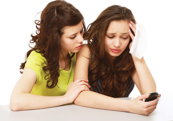 a young girl with a mobile phone crying and a friend calming her