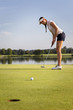 © lichtmeister - Girl golfer putting ball on green.