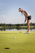 Girl Golfer Putting Ball On Green.