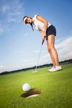 Happy Girl Golfer Putting Ball Into Hole.