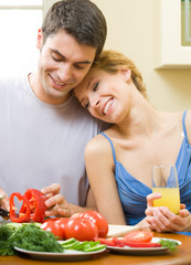 Wall Mural - Cheerful young cooking couple at home