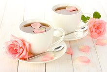 Cups Of Tea With Roses On White Wooden Table