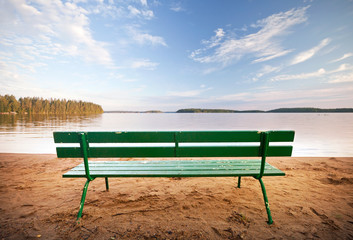 Green bench in front of the lake coast