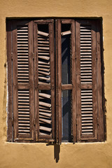 Fototapete - Achient brown window on a mustard yellow house in Sarti, Greece