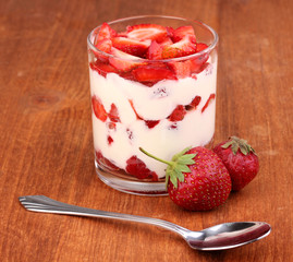 Wall Mural - Glass of ripe strawberries with cream on wooden background