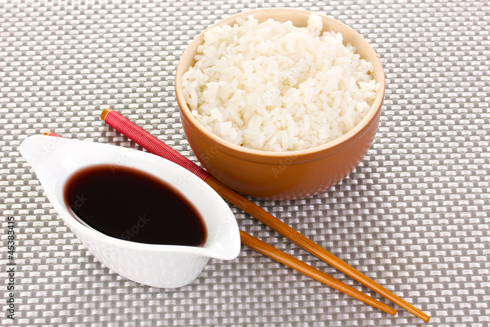 Bowl of rice and chopsticks on grey mat