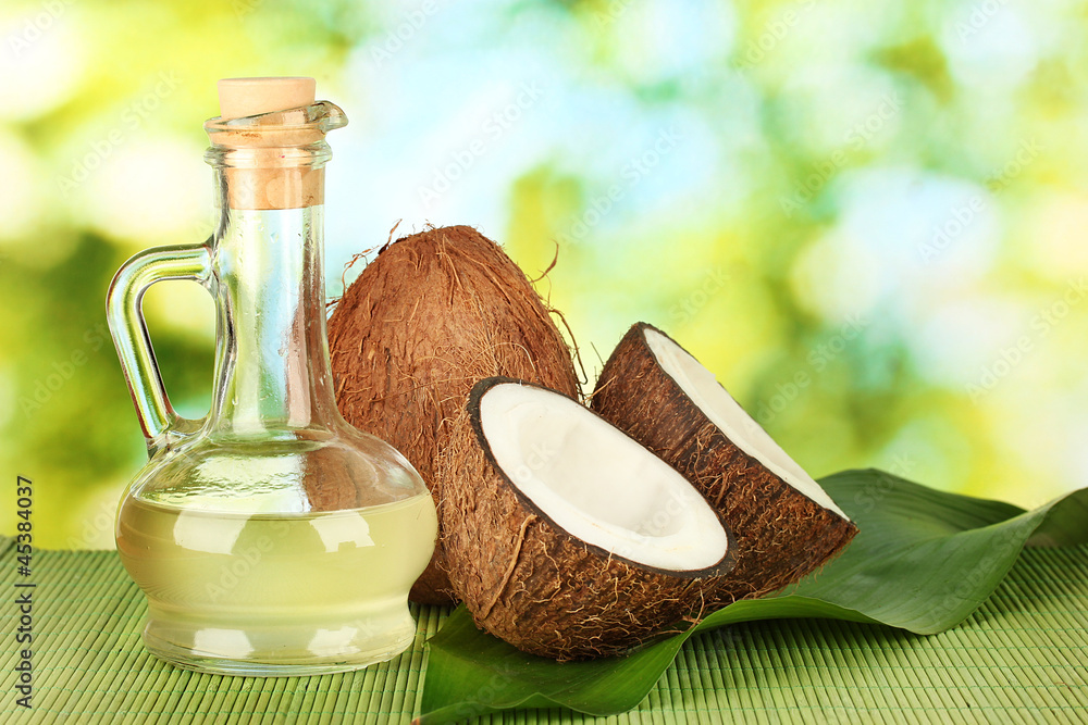 decanter with coconut oil and coconuts on green background