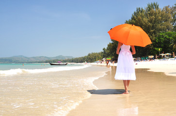 Wall Mural - Girl with an orange umbrella on the sandy beach