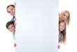 © Andrey Popov - Portrait Of Family Peeping Behind Blank Board