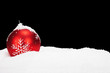 canvas print picture - rote christbaumkugel im schnee vor schwarzem hintergrund