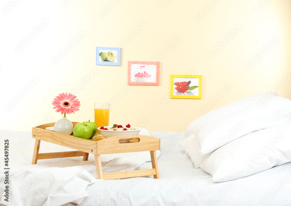 wooden tray with light breakfast on bed