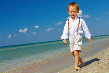 confident baby boy goes forward in firm gait, sea beach