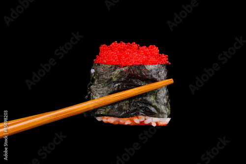 Tapeta ścienna Trzymając sushi pałeczkami na czarnym tle