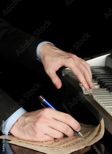 Fotografía man hands playing piano and writes on parer for notes