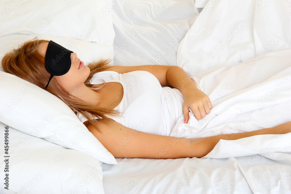 young beautiful woman sleeping in bed with eye mask