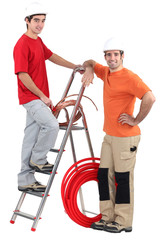 Two electricians with copper coil and ladder