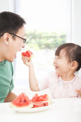 Wall Mural - happy little girl with father eating fruits