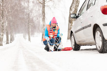 Woman with tire chains car snow breakdown