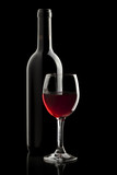 Fototapeta Panele - Elegant red wine glass and a wine bottle in black background