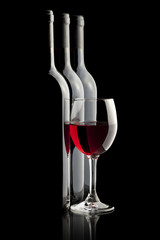 Elegant red wine glass and a wine bottles in black background